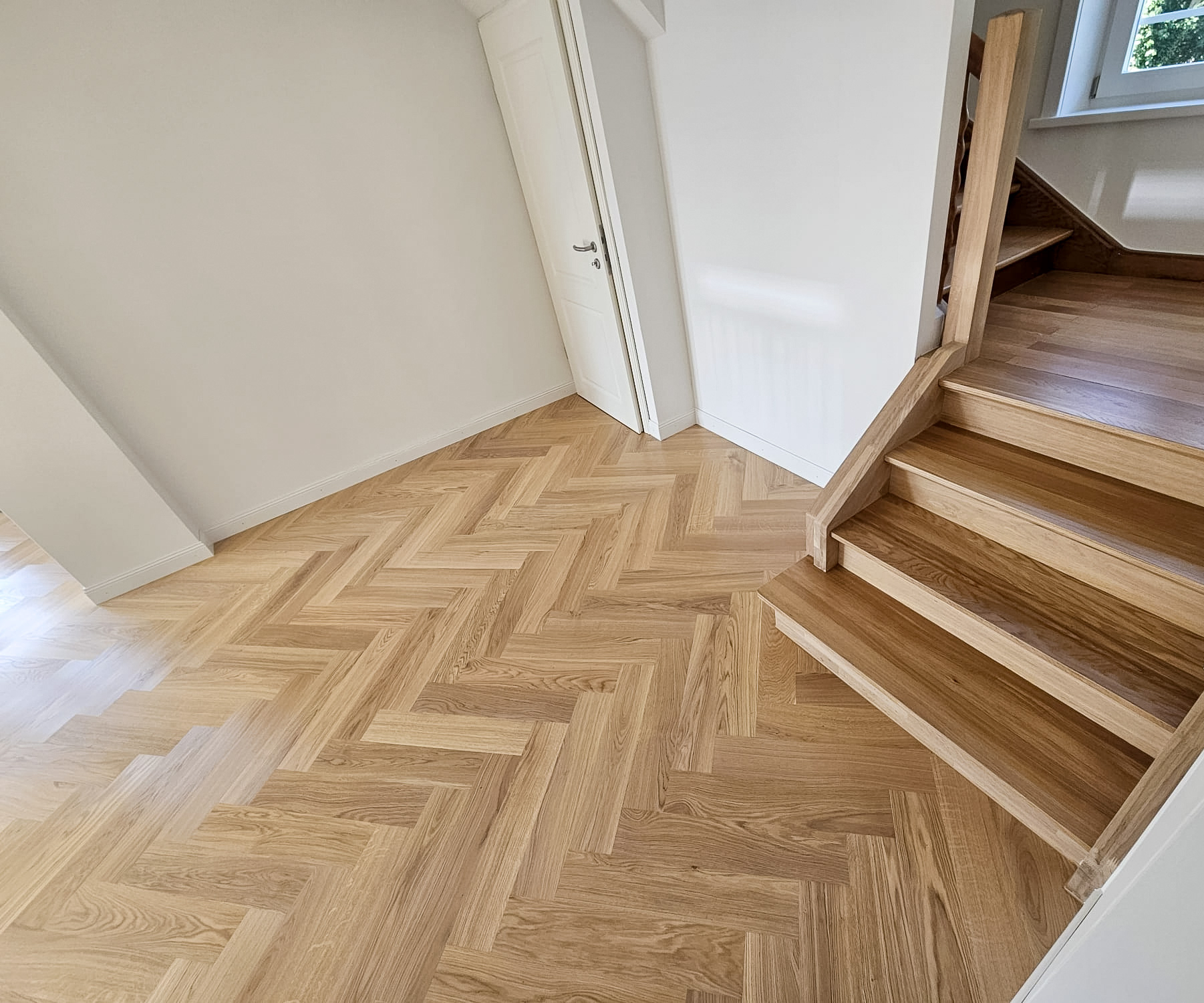 Fertig verlegtes Eichenparkett im Fischgrat mit Treppe